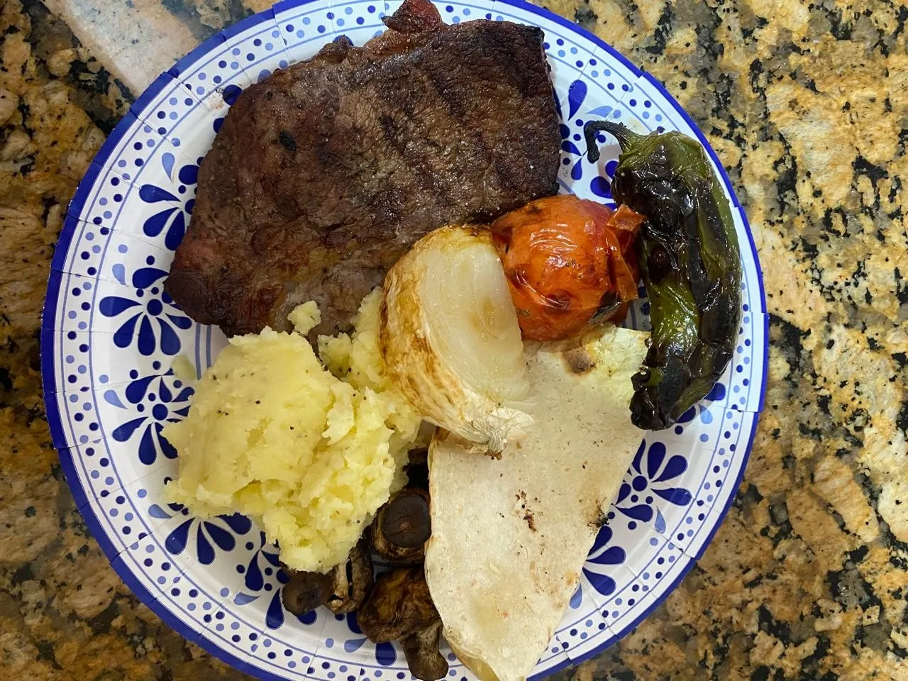 Plato de talavera con carne asada, puré de papa, cebolla y chile asados y una tortilla