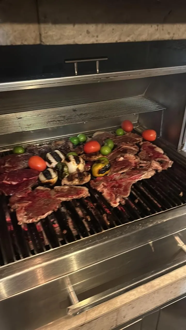 Asador de acero inoxidable con carne, champiñones, jitomates y chiles